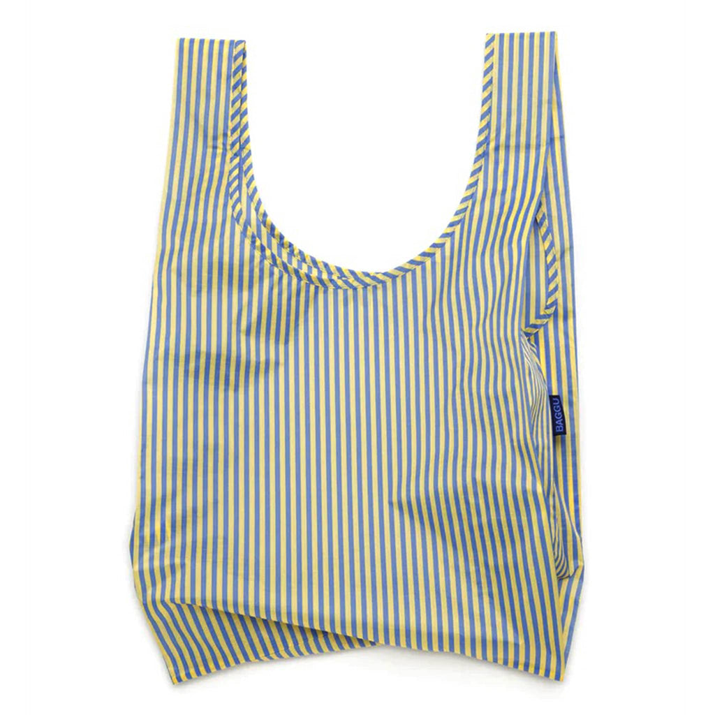 Baggu standard size eco-friendly recycled ripstop nylon reusable tote bag with yellow and blue thin stripe print, unfolded.