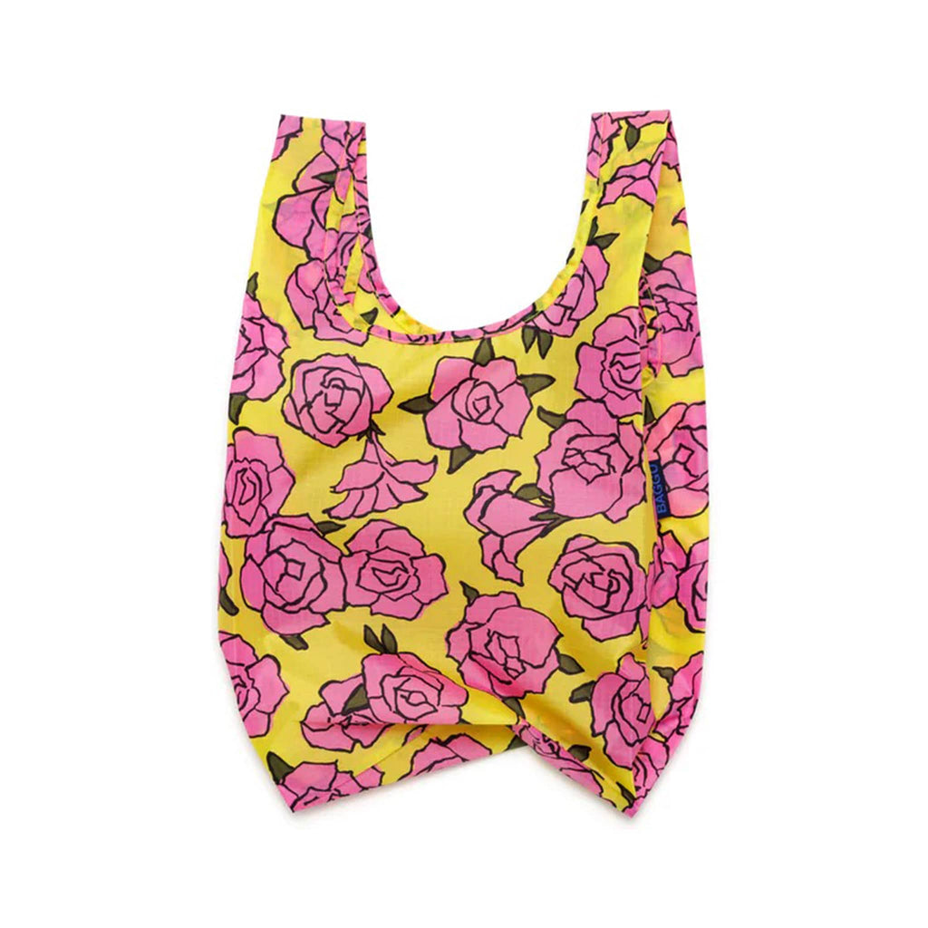 Baggu baby size eco-friendly recycled ripstop nylon reusable tote bag with a pink Rose pattern on a yellow background, unfolded.