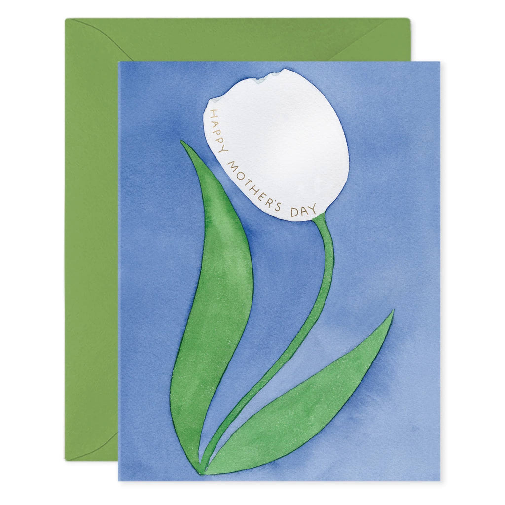 E. Frances Paper Tulip Mom greeting card with a single white tulip illustration on a blue backdrop and "happy mother's day" in gold foil lettering, front of card shown with a green envelope.