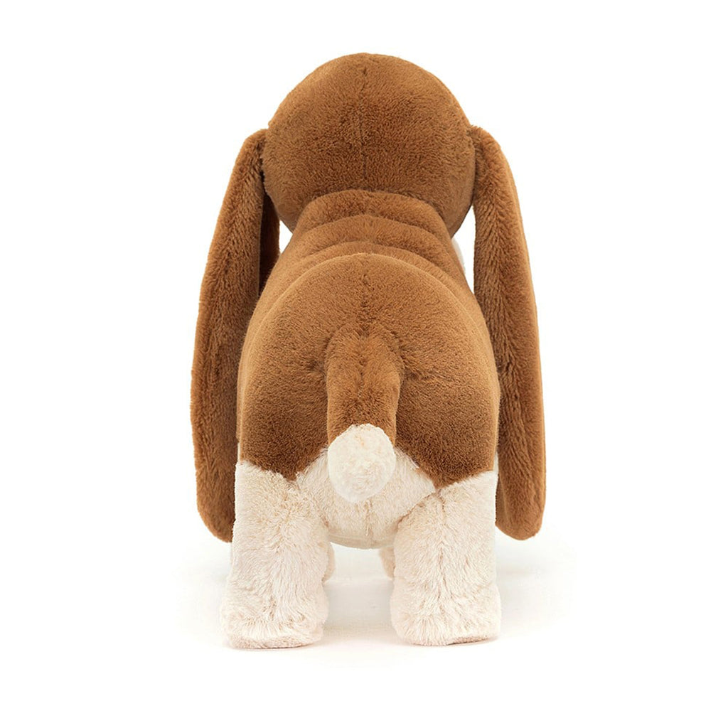 Jellycat Randall Basset Hound plush toy with brown and cream fur, long ears, black bead eyes and black nose in standing position, back view.