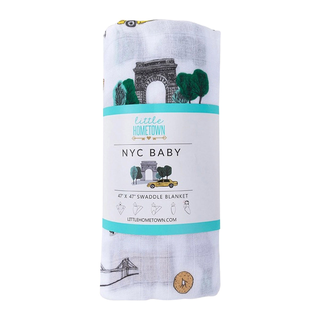 Little Hometown NYC Baby Swaddle Blanket made from a bamboo and cotton blend muslin with illustrations of NYC icons on a white background, shown with belly band packaging.