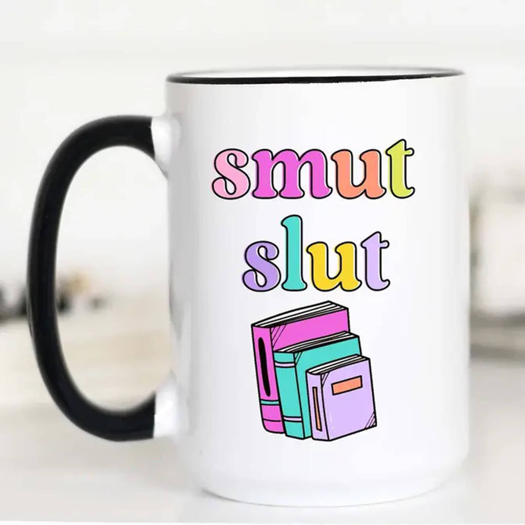 Mugsby white ceramic mug with black handle and rim with an illustration of colorful books and "smut slut" in colorful lettering.