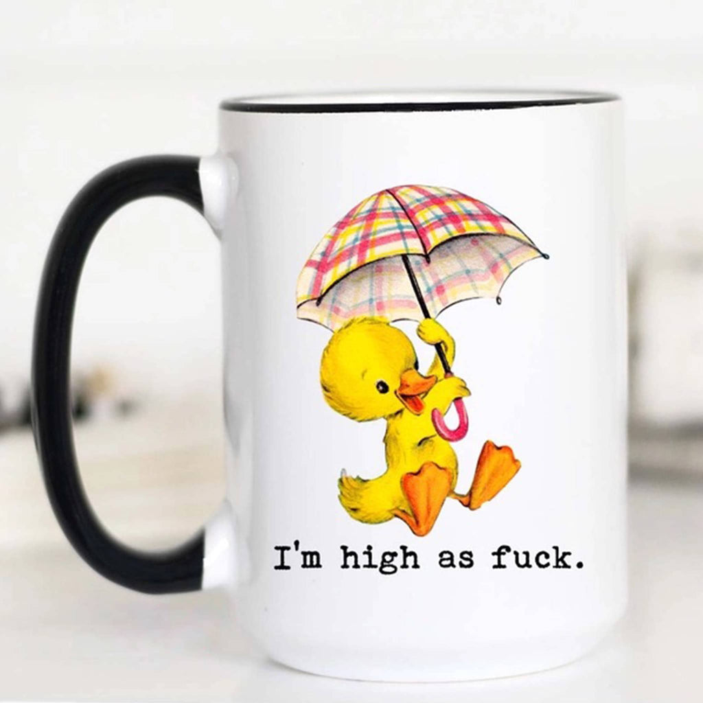 Mugsby white ceramic mug with black handle and rim with an illustration of a yellow duckling holding a plaid umbrella and "i'm high as fuck" in black lettering.