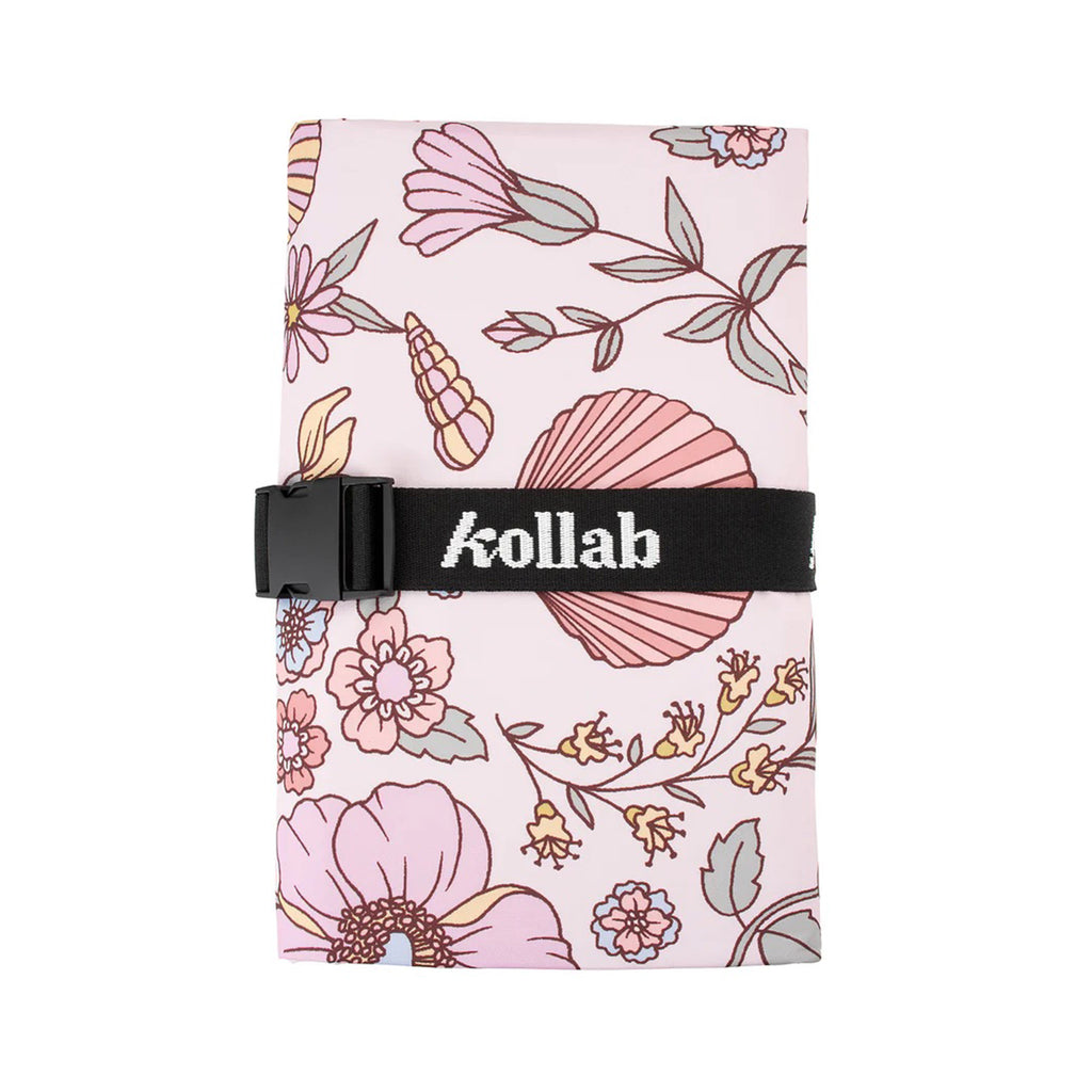 Kollab outdoor mini picnic mat with water resistant fabric construction and covered in a shell and floral print on a pastel pink background, with adjustable strap for storage.