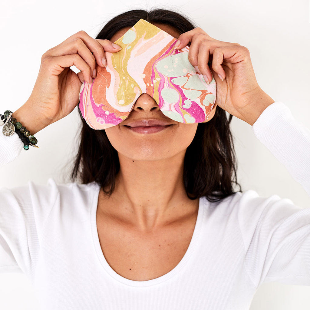 love mert heart shaped love eye pillow in paradiso color scheme with blue, orange, pink and yellow swirls on model