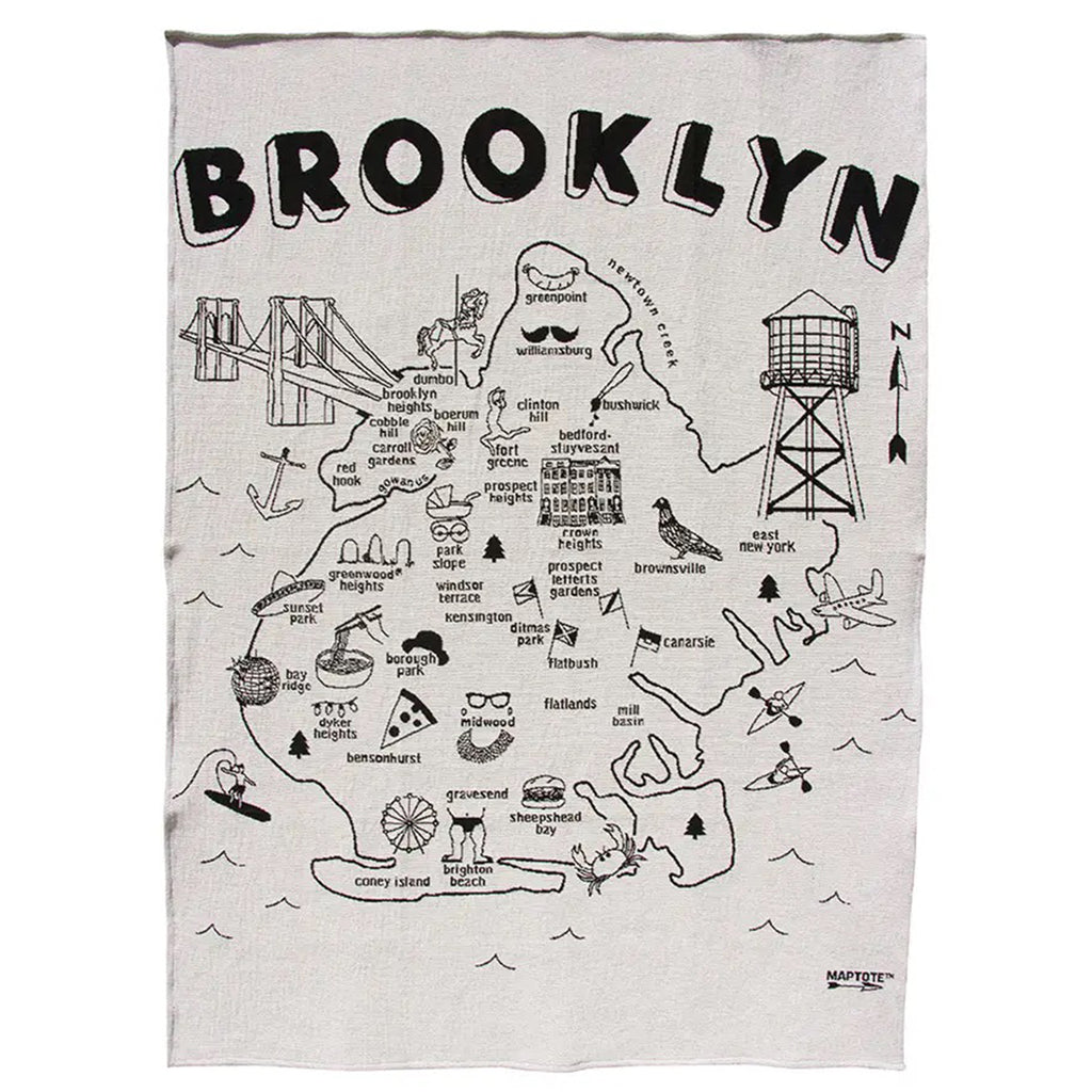 Overall of knit throw blanket with "brooklyn" at the top, the outline of the borough with neighborhood names and illustrations of various Brooklyn icons in black on a white backdrop.