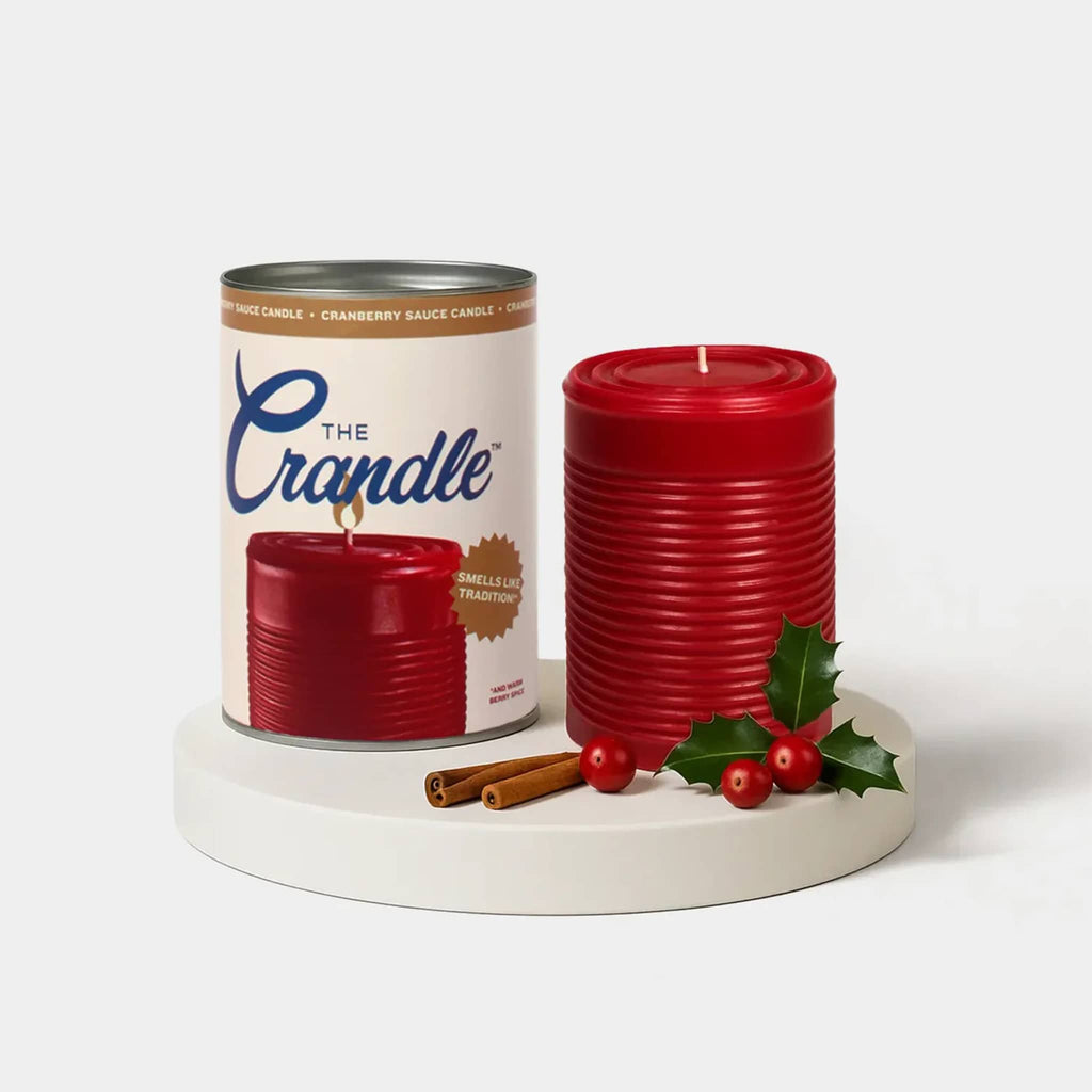 Red candle that looks like canned cranberry sauce beside can packaging, on a white background. 