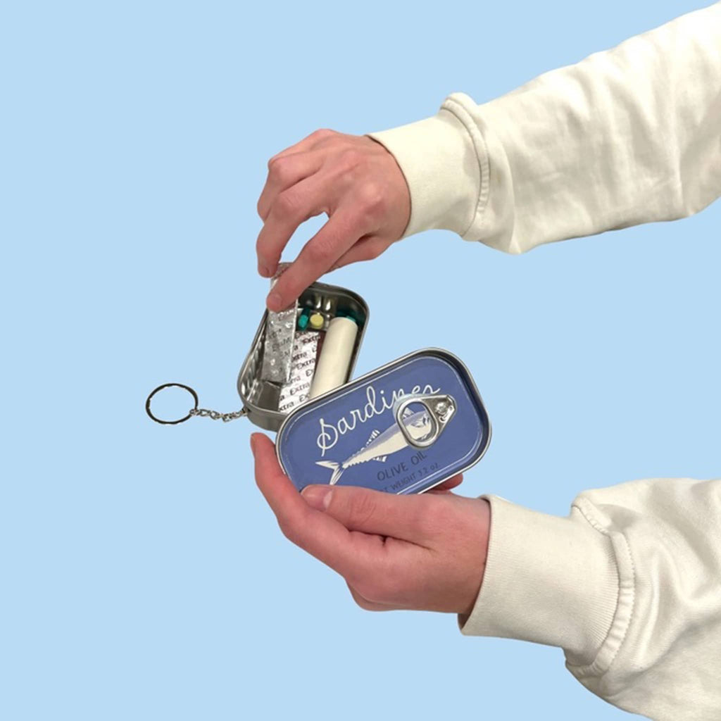 NPW Sardine Tin keychain, with hand showing how to open and gum and mints inside.