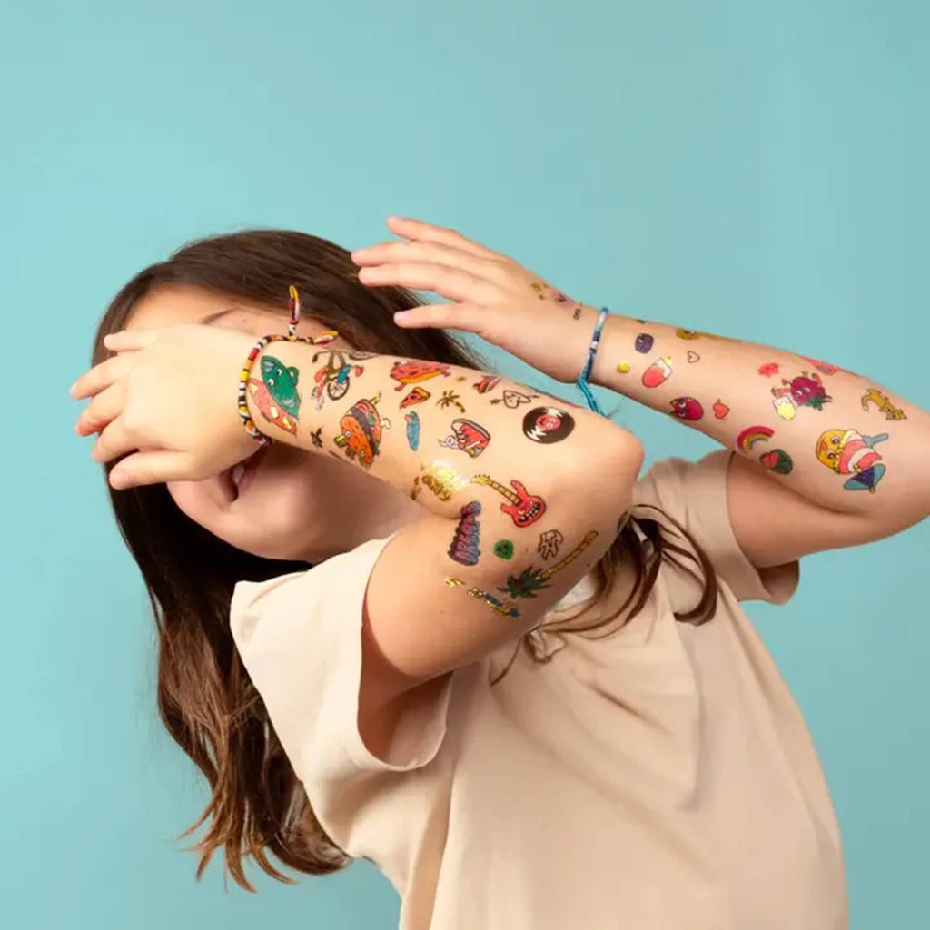 OMY Kawaii kids temporary tattoos, child shown with samples of some of the tattoos on their arms.