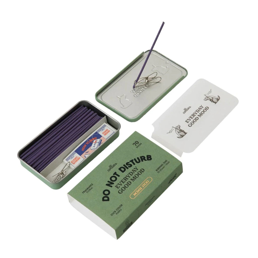 Ameico Collins Do Not Disturb floral scented incense sticks in green tin packaging, open with contents shown including outer sleeve and an incense clip holding a purple incense stick on the overturned lid.