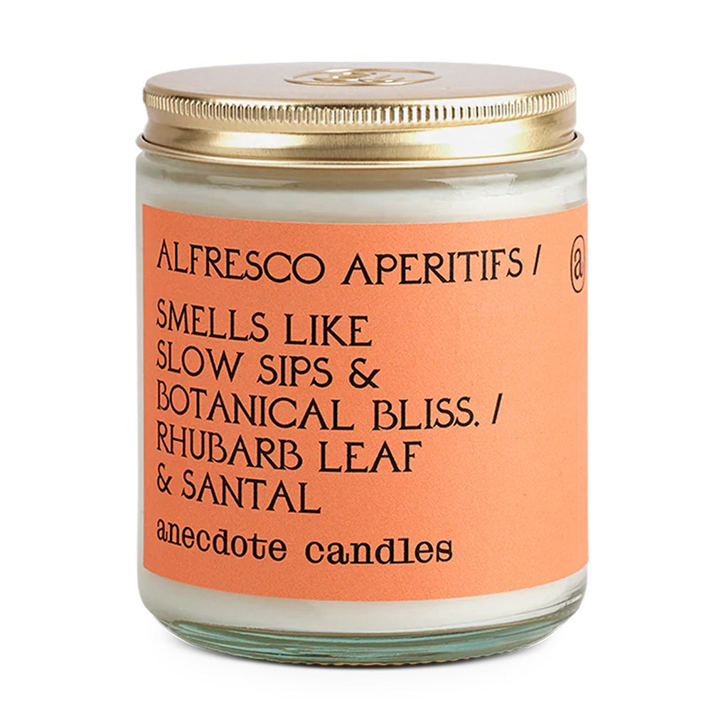 Anecdote Alfresco Apertifs candle with rhubarb leaf and santal scented coconut soy wax blend in a clear glass jar with gold lid and orange label.