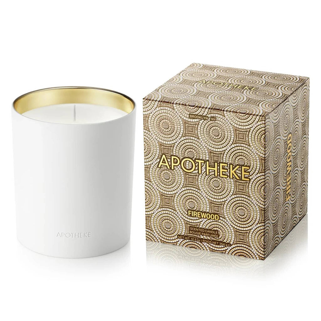 Apotheke Firewood 12.5 ounce scented candle in white ceramic vessel with gold interior, shown beside tan art deco printed box.