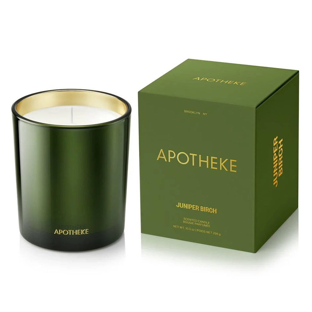 Apotheke Juniper Birch scented limited edition soy blend candle in dark green glass vessel beside matching green box with gold lettering.