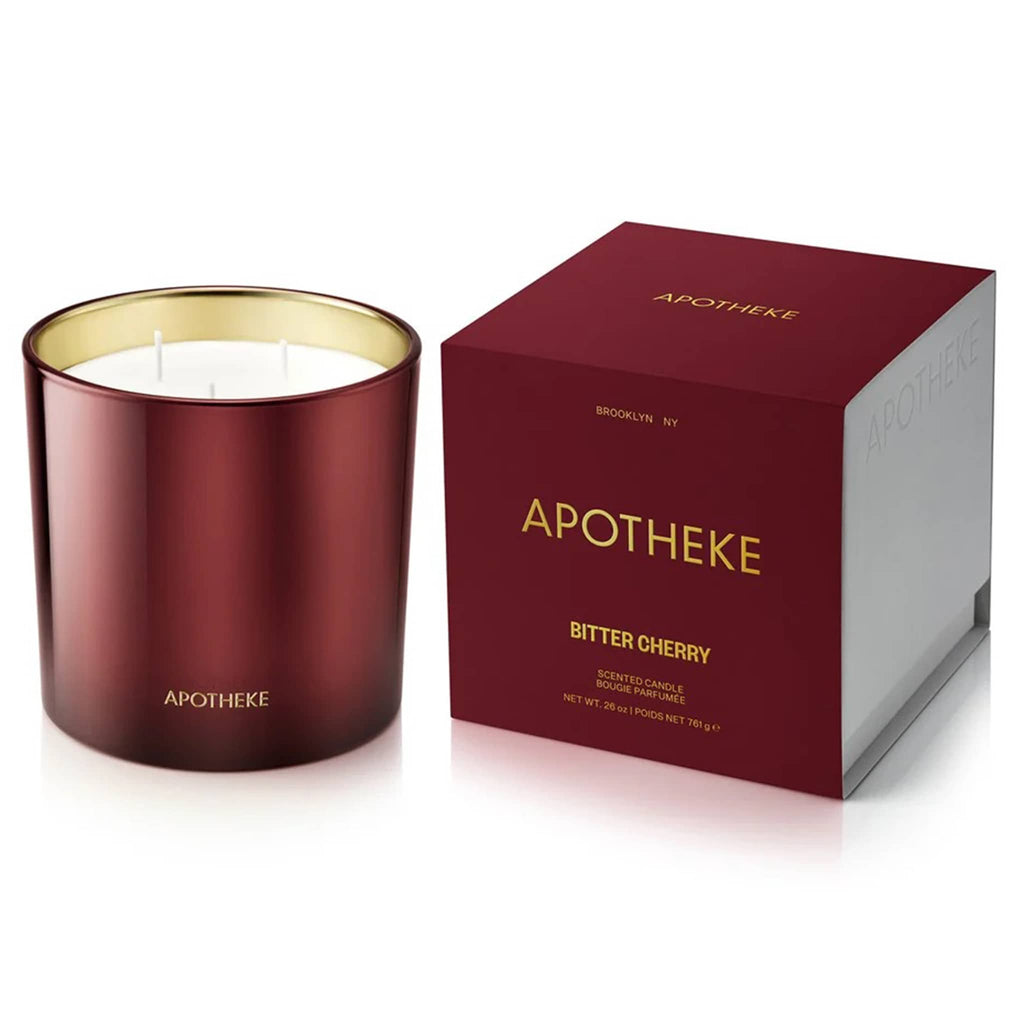 Apotheke 26 ounce Bitter Cherry scented soy wax blend 3 wick candle in deep cherry red glass vessel with gold interior, next to matching gift box.