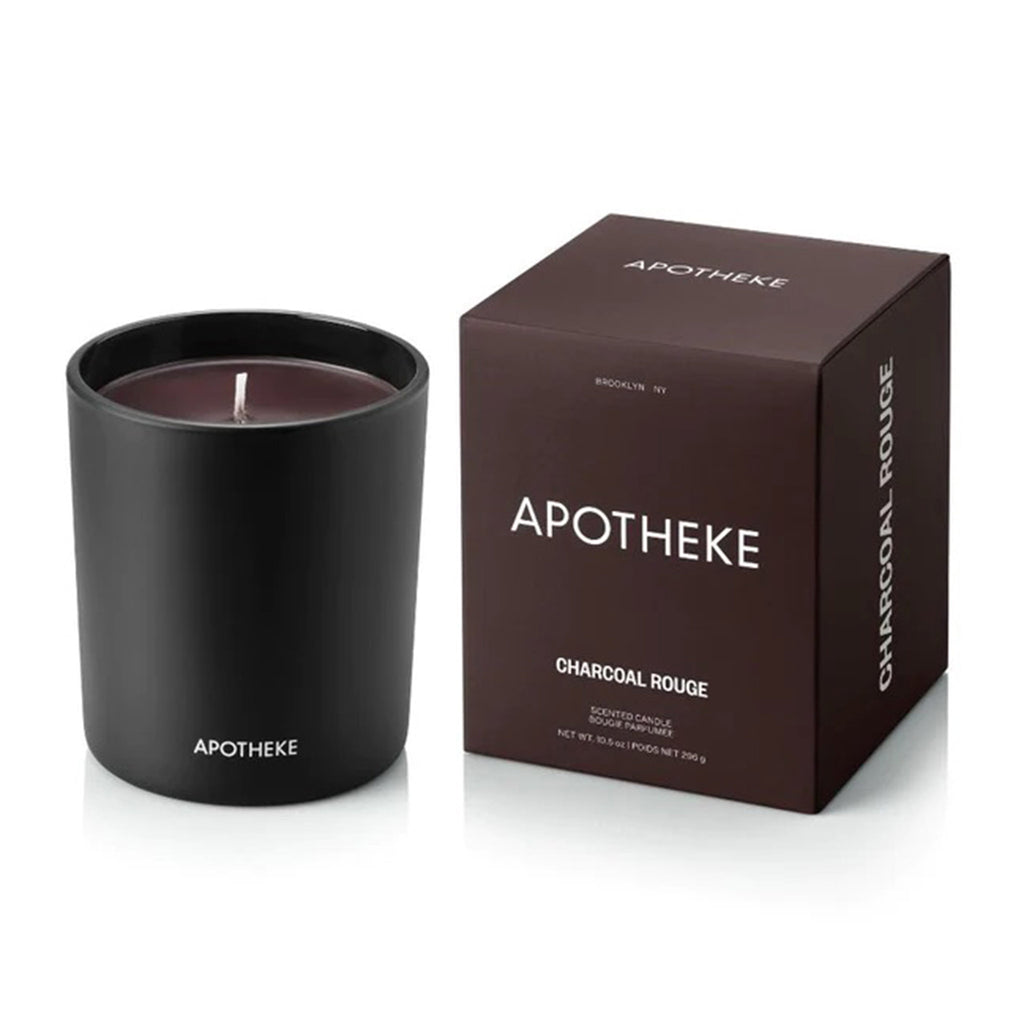 Apotheke Charcoal Rouge scented soy wax blend candle in matte black glass vessel with dark rouge hued wax and gift box, slightly overhead view.