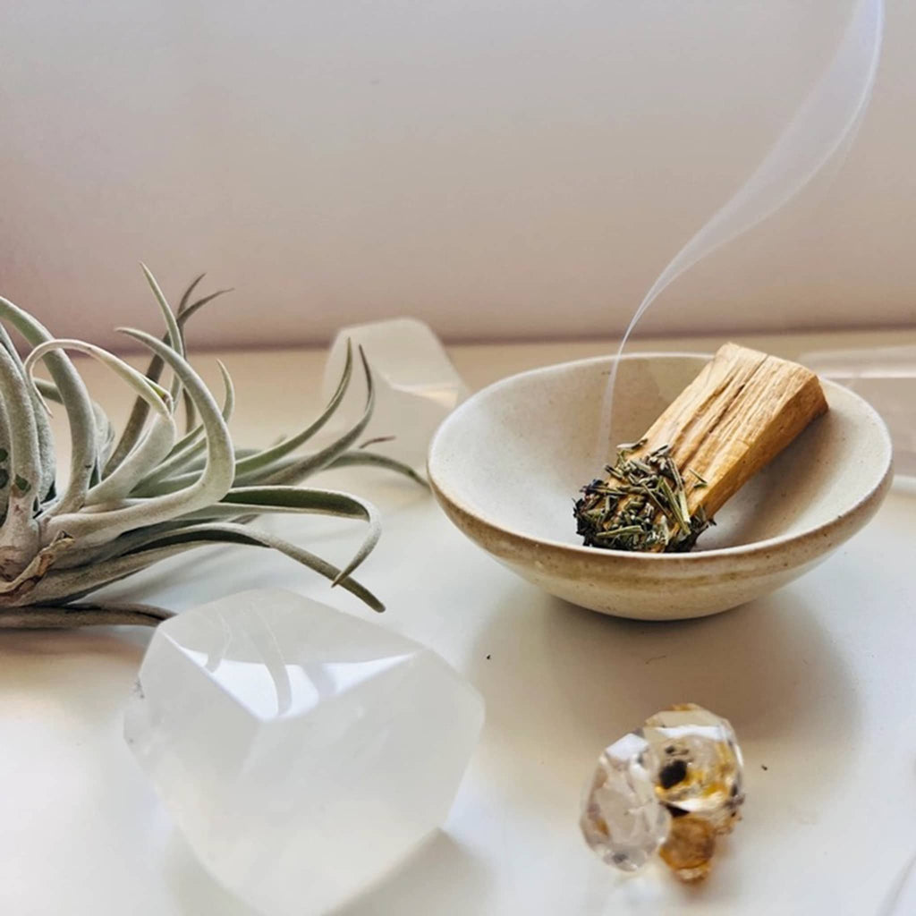 Ark Made Dipped Palo Santo Stick, lit in a bowl with crystals and a succulent.