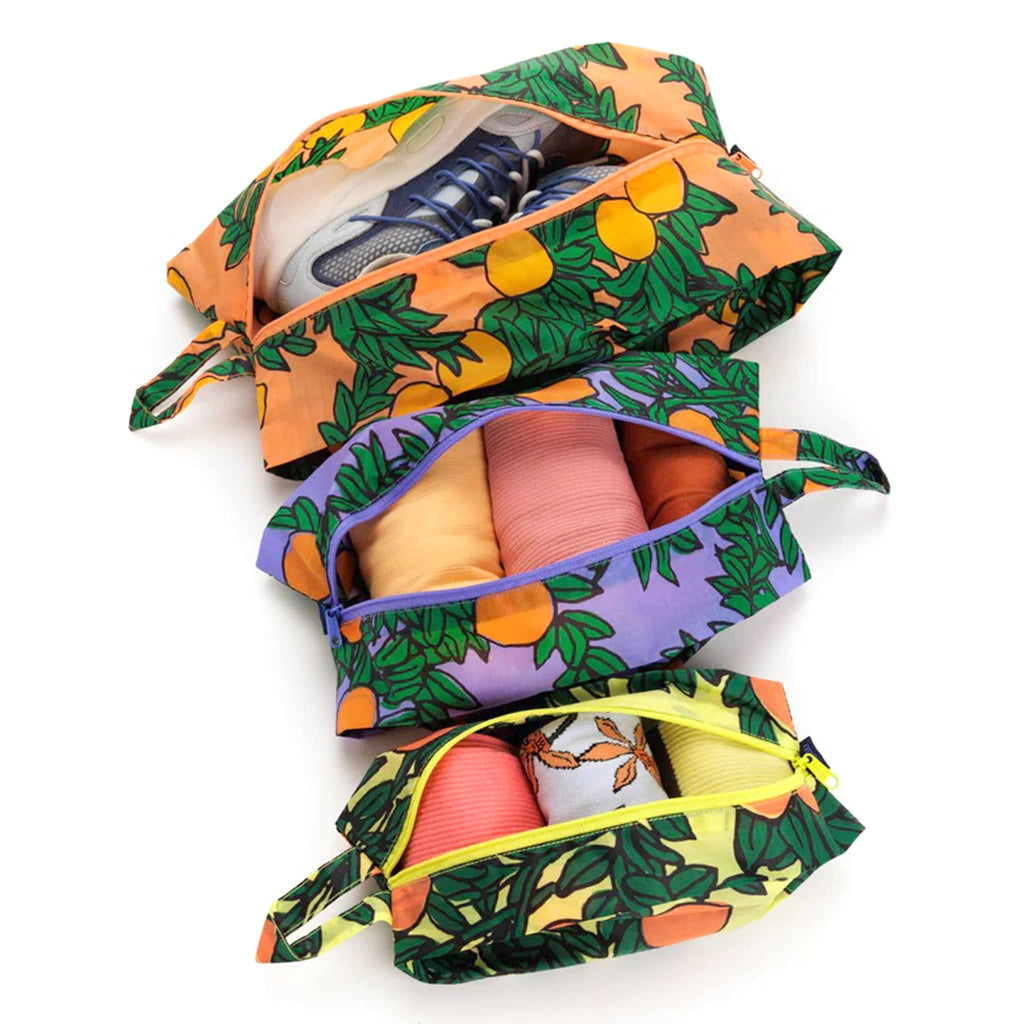 Baggu reusable recycled ripstop nylon 3D zip bags, set of 3 in Orange Trees print, unzipped and filled with shoes and clothing.