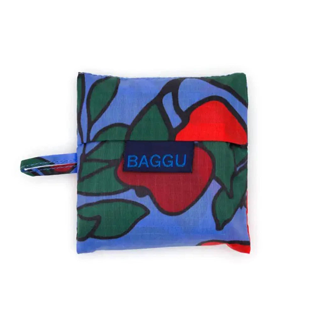 Foldable shopping bag with colorful leaf and red apple pattern in matching pouch with 'BAGGU' branding on a white background.