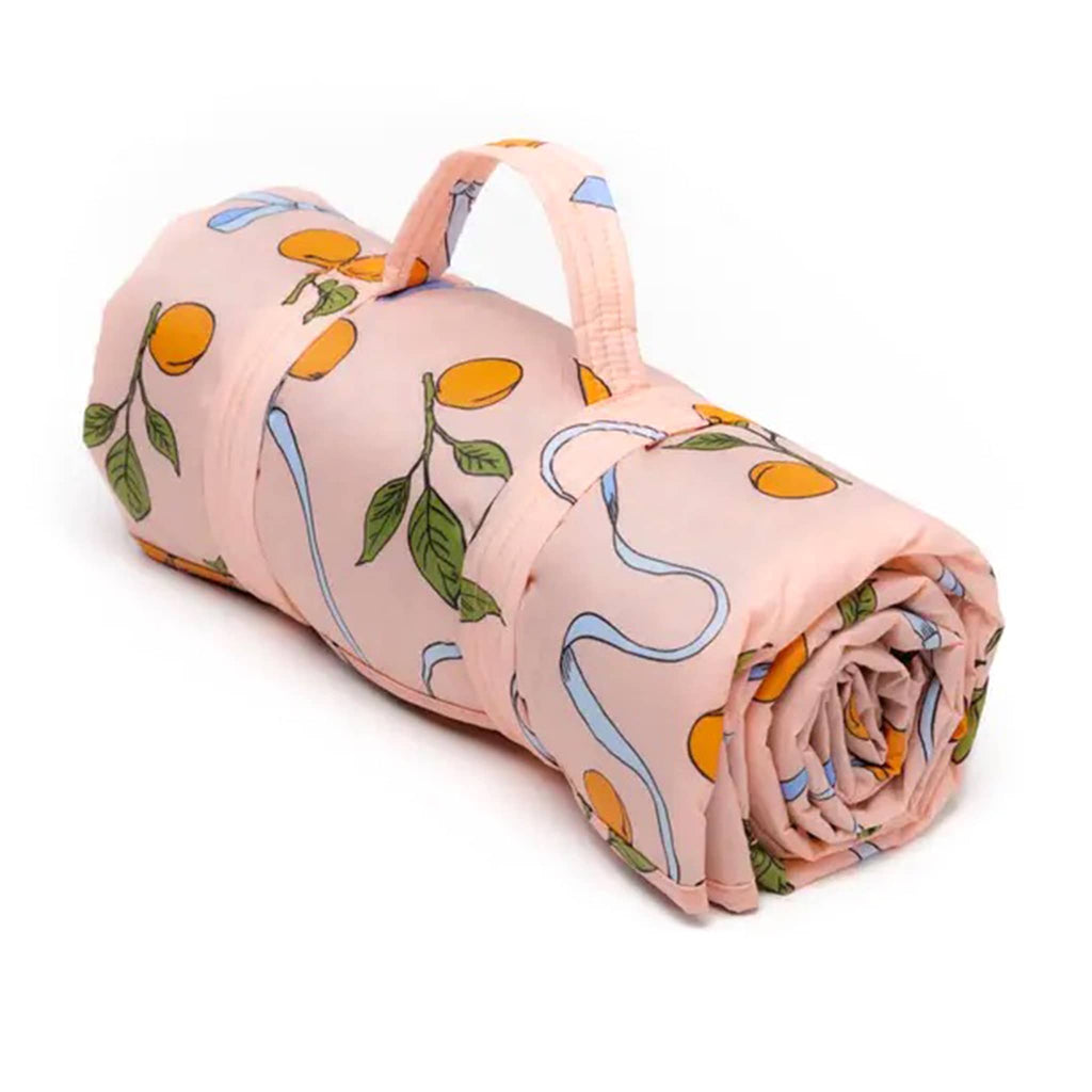 Baggu Puffy Picnic Blanket in Apricots and Ribbons print, rolled up.