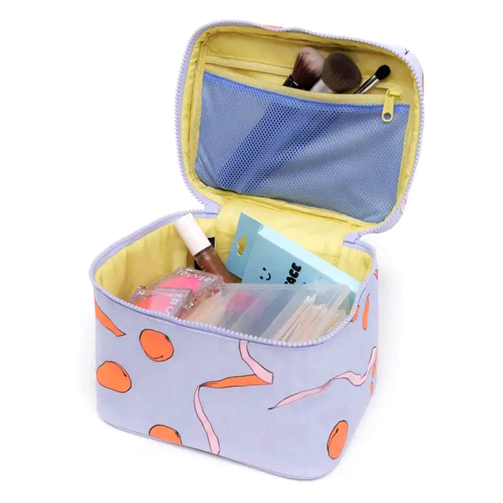 Baggu large cosmetic case with apricots and ribbons print, open with makeup inside.