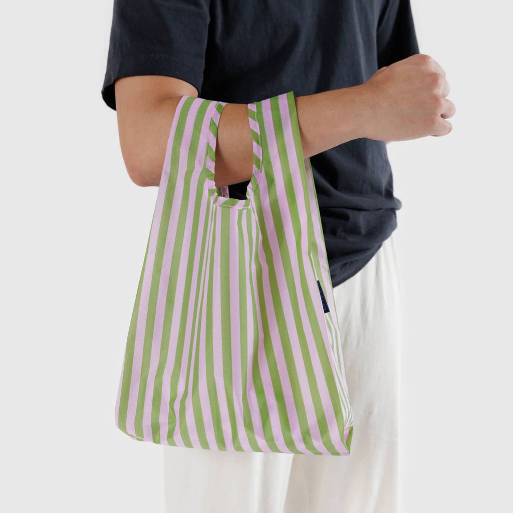 Baggu baby size eco-friendly recycled ripstop nylon reusable tote bag in Avocado Candy Stripe pattern, on model's arm.