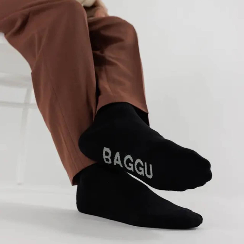 Person wearing brown pants and black ribbed socks with 'BAGGU' logo on a light background.