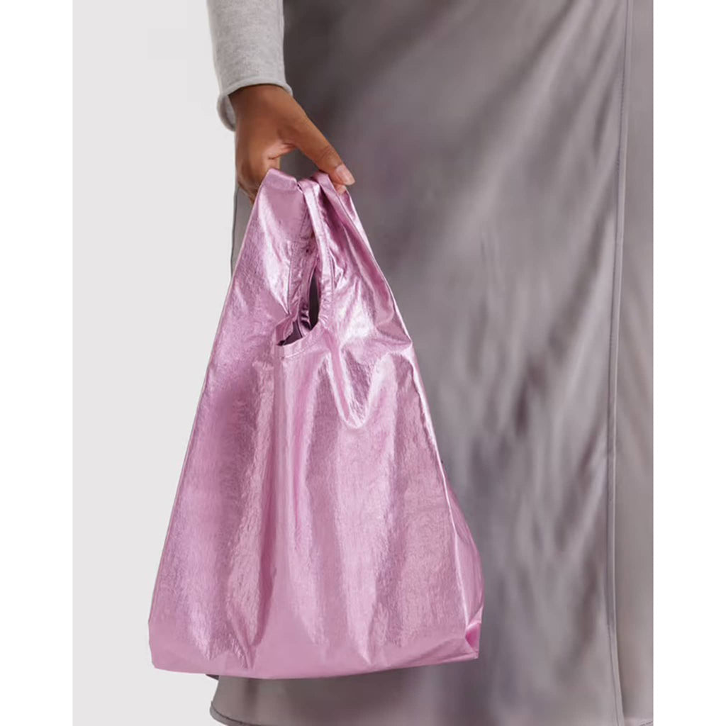 Person holding a metallic pink reusable bag against a neutral background.
