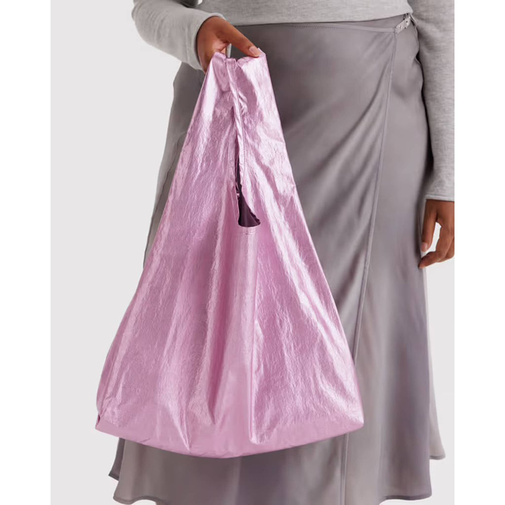 Person holding a pink metallic reusable nylon bag with a plain background.