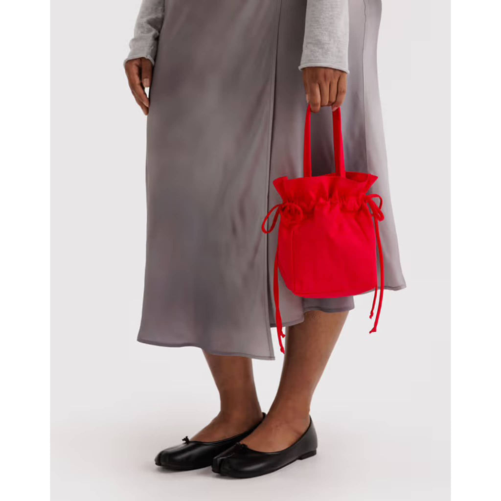 Person holding a red drawstring bag against a white background.