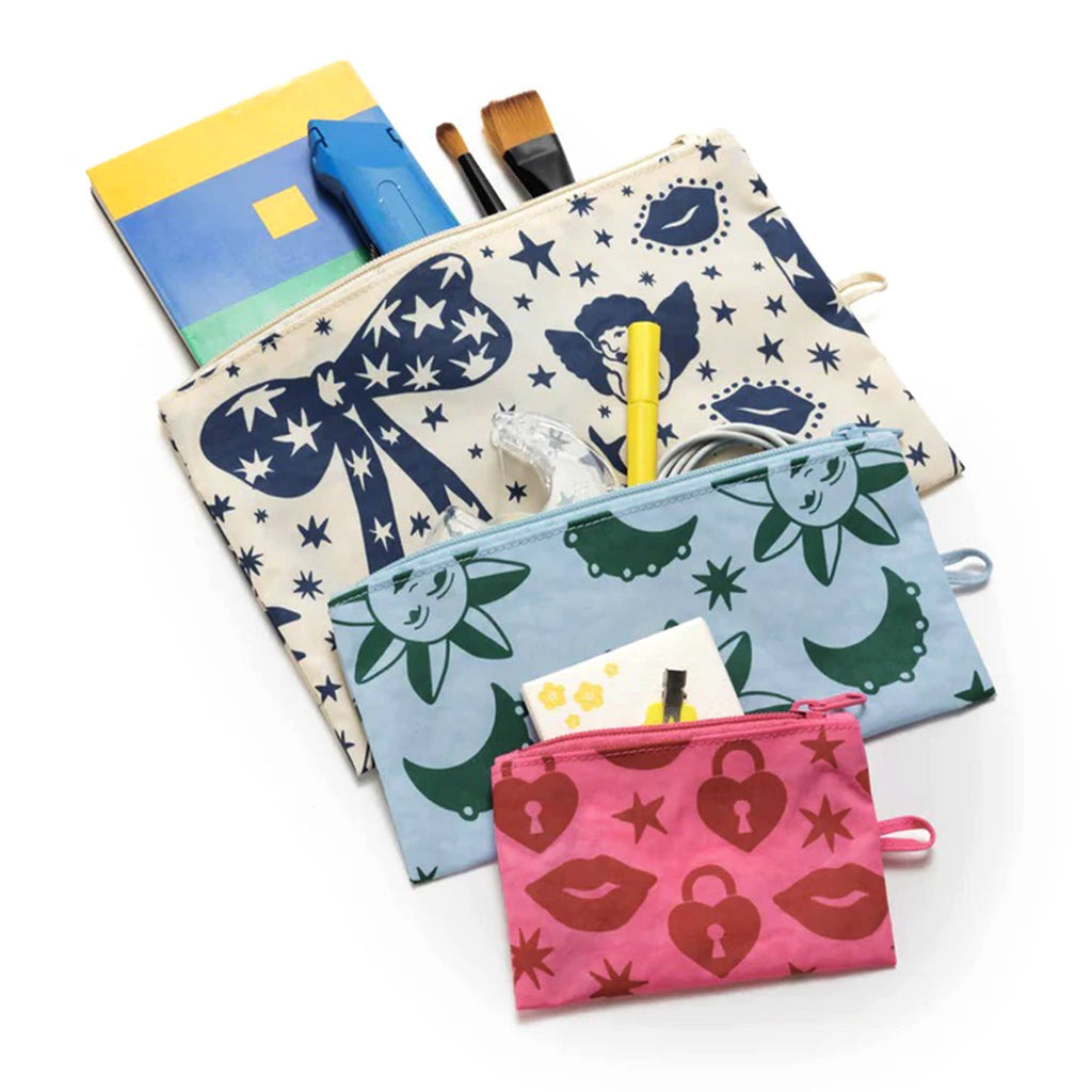 Baggu recycled ripstop nylon flat zipper pouches, set of 3 in assorted sizes with prints from the Charm collection, flat and unzipped with art and office supplies coming out of the tops.