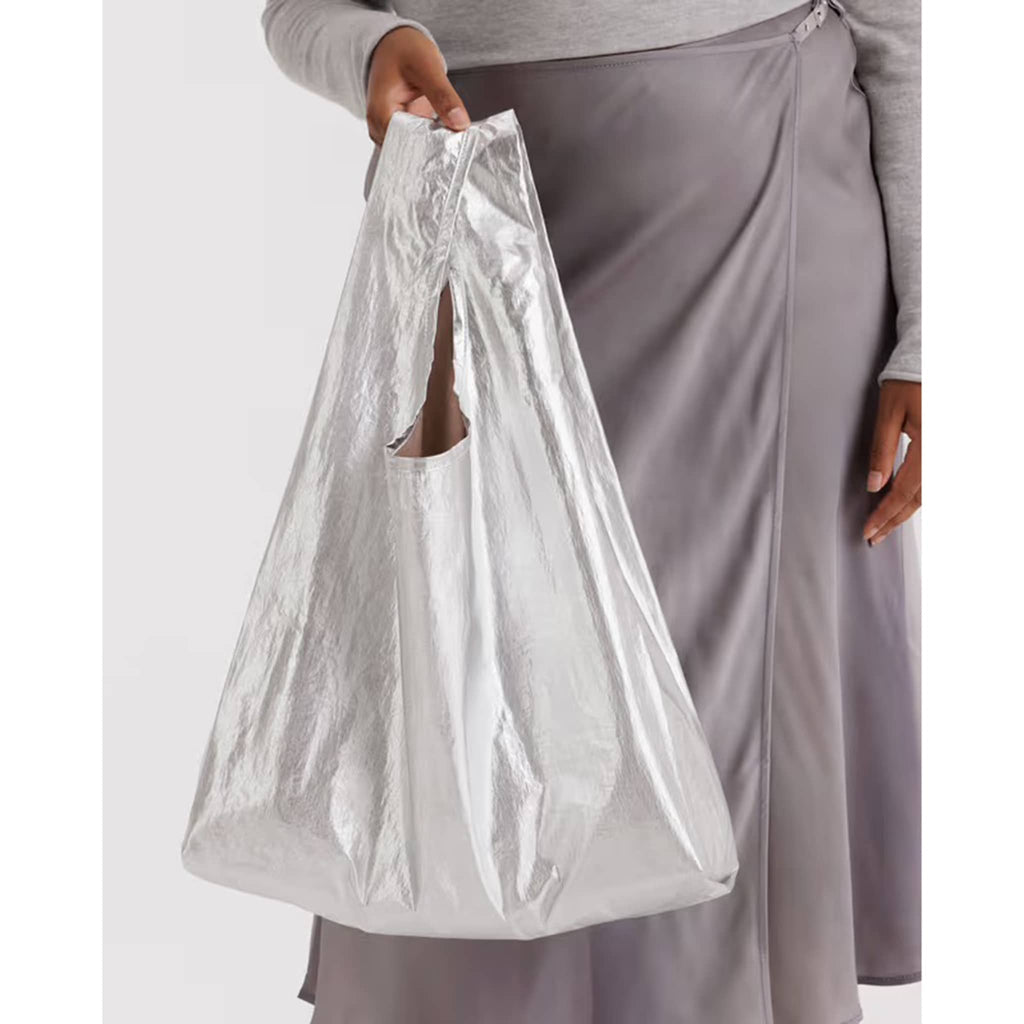 Person holding a silver nylon reusable bag against a white background.