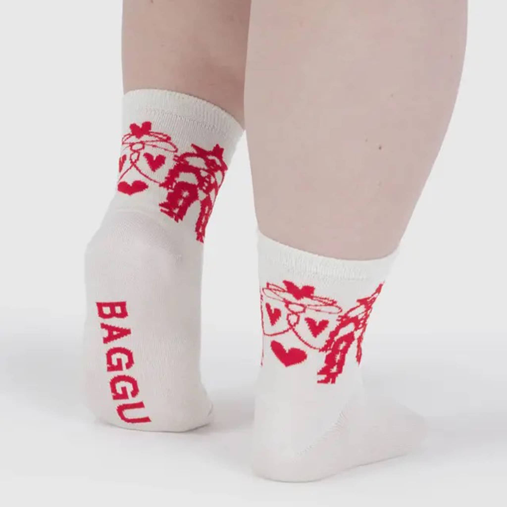 White socks with red Cowgirl graphics and 'BAGGU' branding on a persons feet, on a white background.