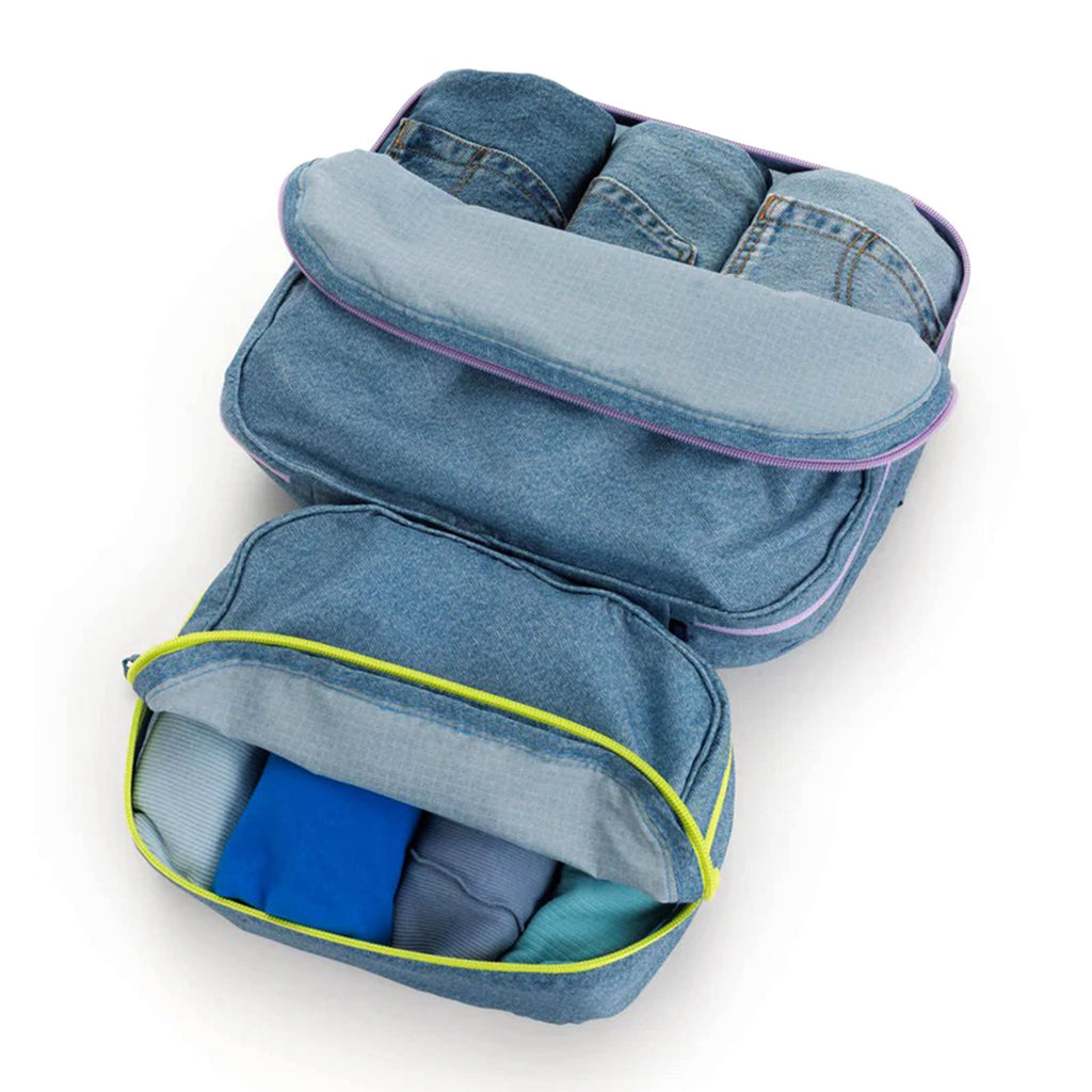 Baggu reusable recycled ripstop nylon packing cube set of 2 in digital denim print, large cube has a lilac zipper and the small cube has a chartreuse zipper, partially unzipped and filled with clothing.