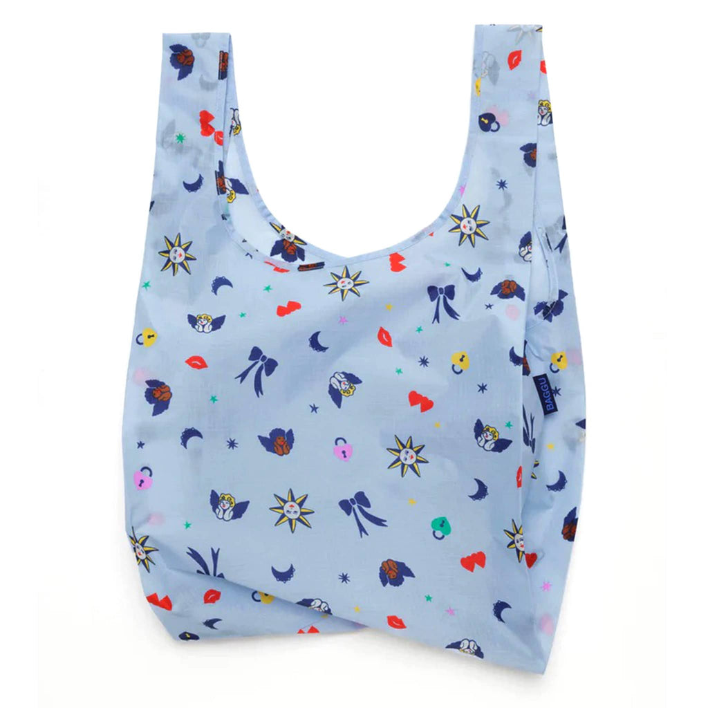 Baggu standard size eco-friendly recycled ripstop nylon reusable tote bag with Ditsy Charms print on a light blue backdrop, unfolded.