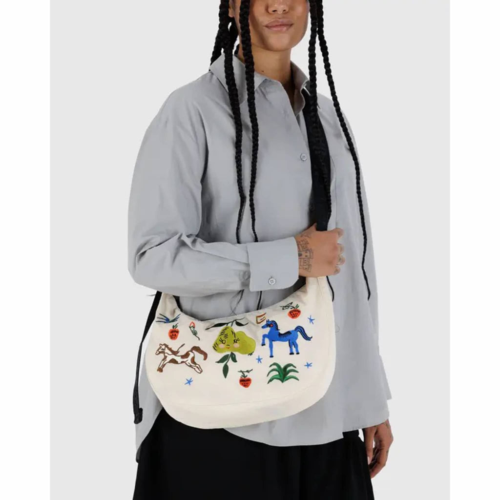 Person holding a Baggu Embroidered Painted Prairie medium ripstop nylon crescent bag.