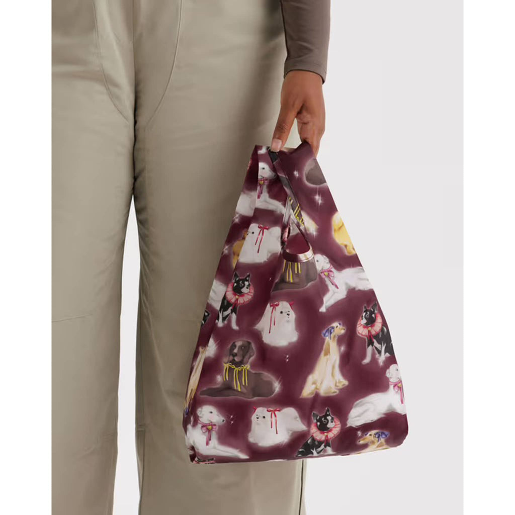 Person holding a purple bag with dog illustrations on a plain background.