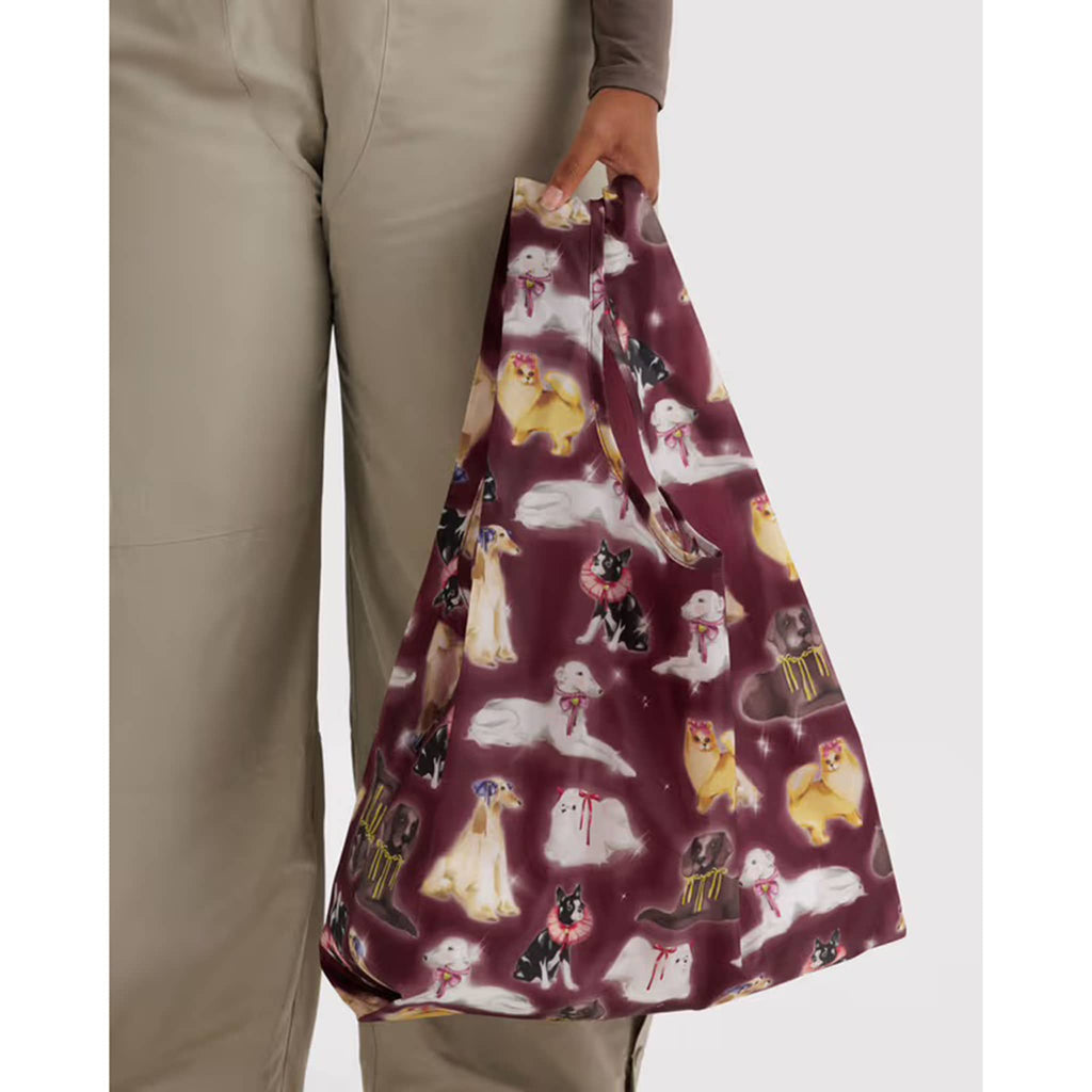 Person holding a purple bag with dog pattern against a white background.