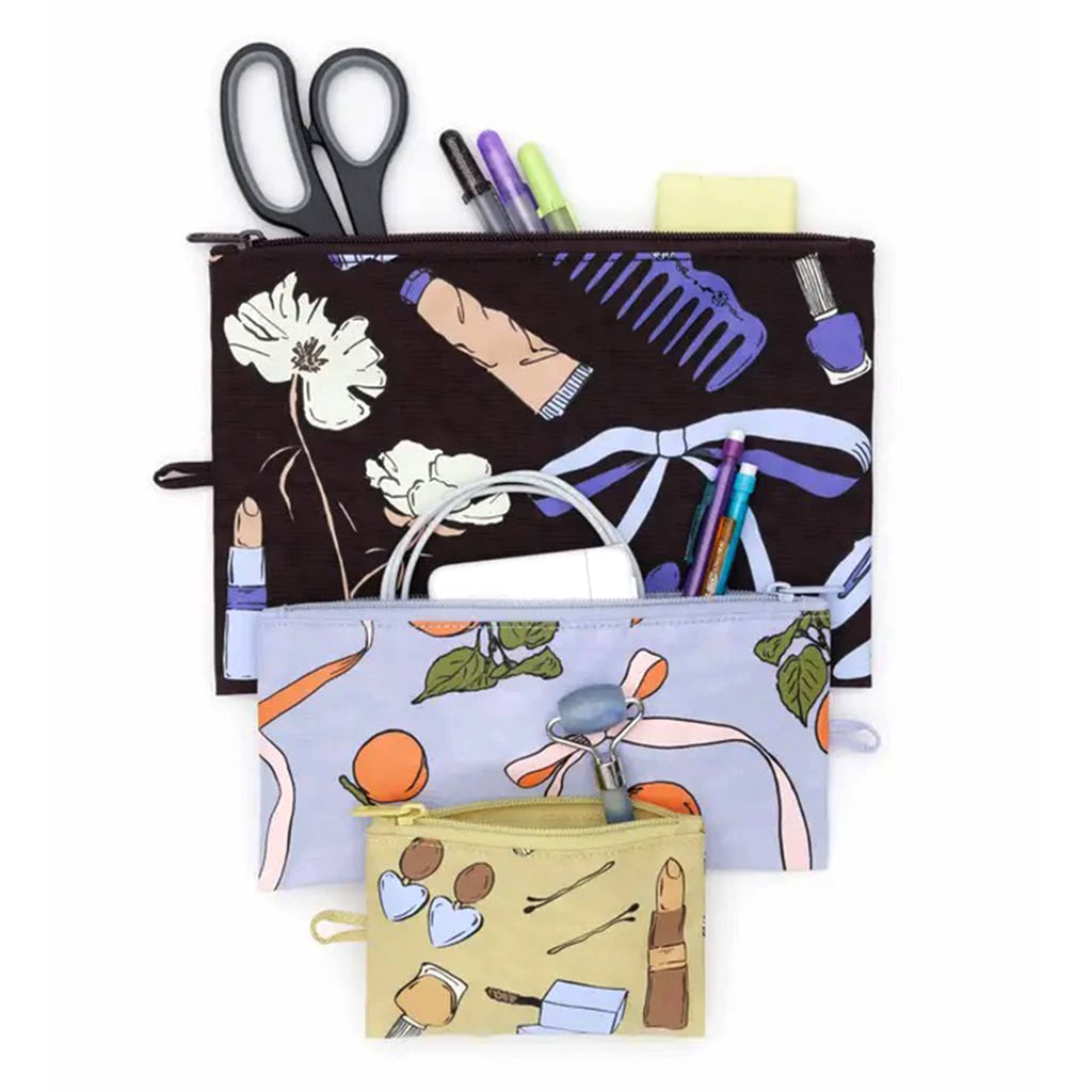 Baggu flat zipper pouch trio in Get Ready With Me collection prints, open with various items coming out of the top.