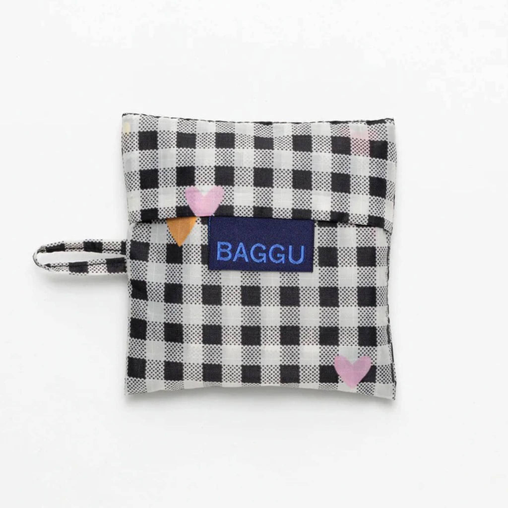 Baggu baby size eco-friendly recycled ripstop nylon reusable tote bag with tiny colorful hearts on a white and black gingham backdrop, in matching pouch.