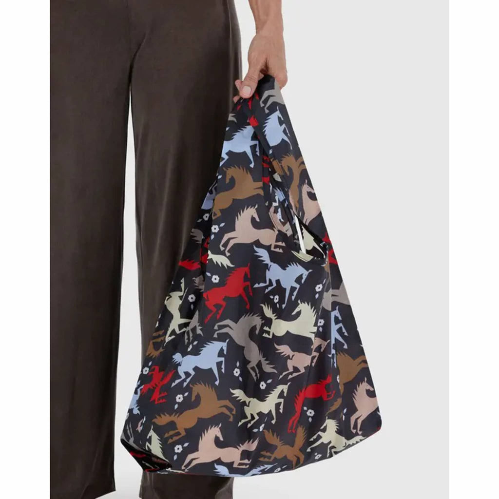 Person holding a reusable bag with horse pattern on a white background
