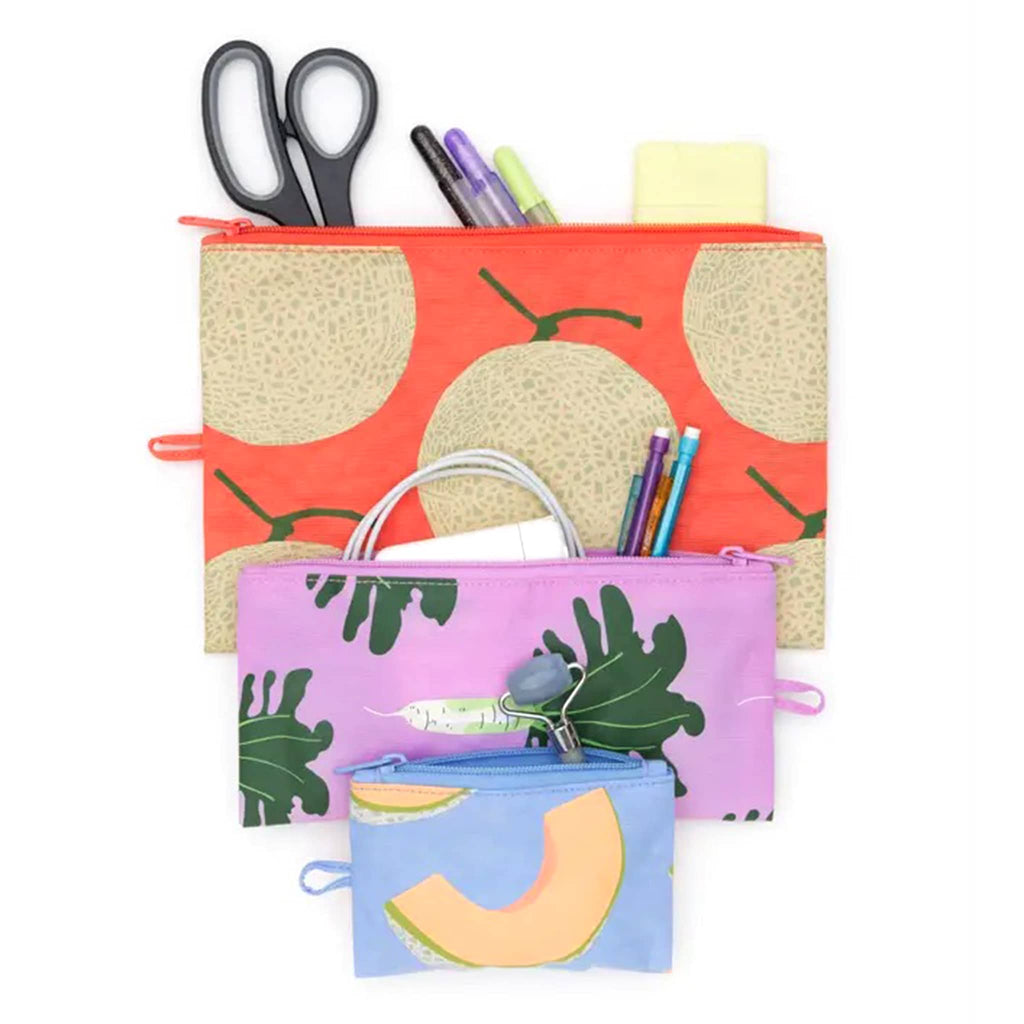 Baggu flat zipper pouch trio in Japanese Produce collection prints, open with various small items coming out of the top.