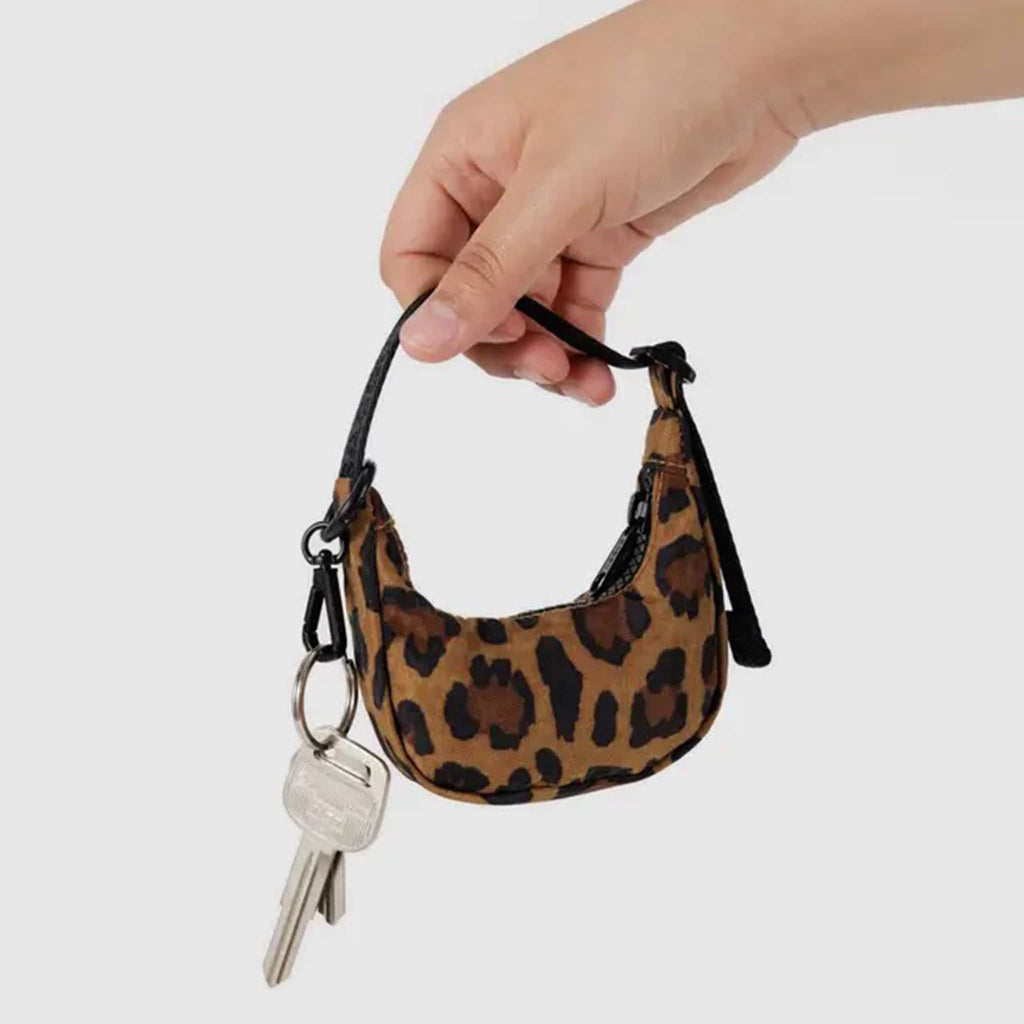 Baggu leopard print crescent bag charm with black strap and keys attached held by a hand.