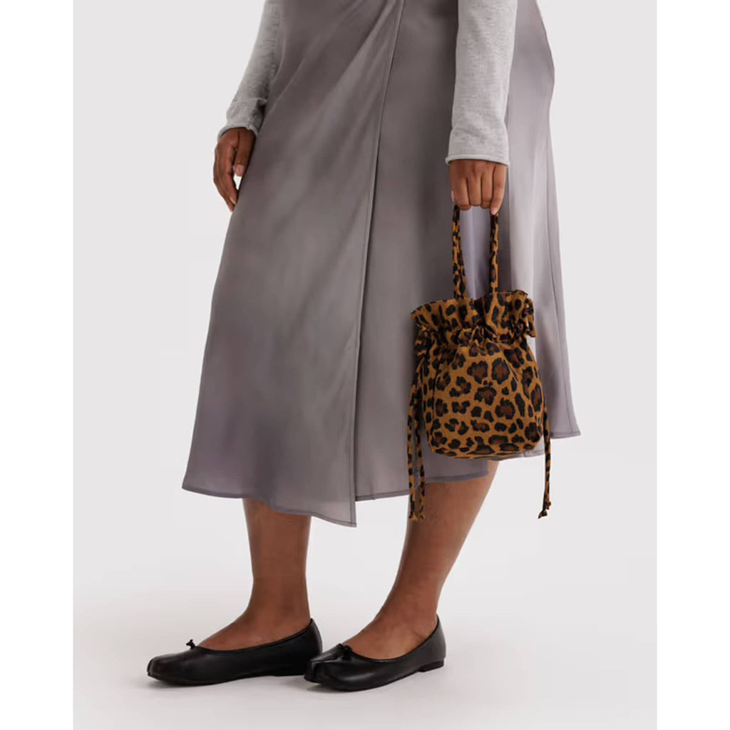 Person holding a leopard print drawstring bag with a plain background.