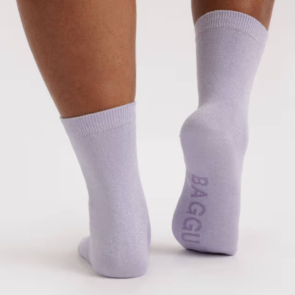 Light purple metallic thread socks on model with 'BAGGU' branding on the sole, on a white background.