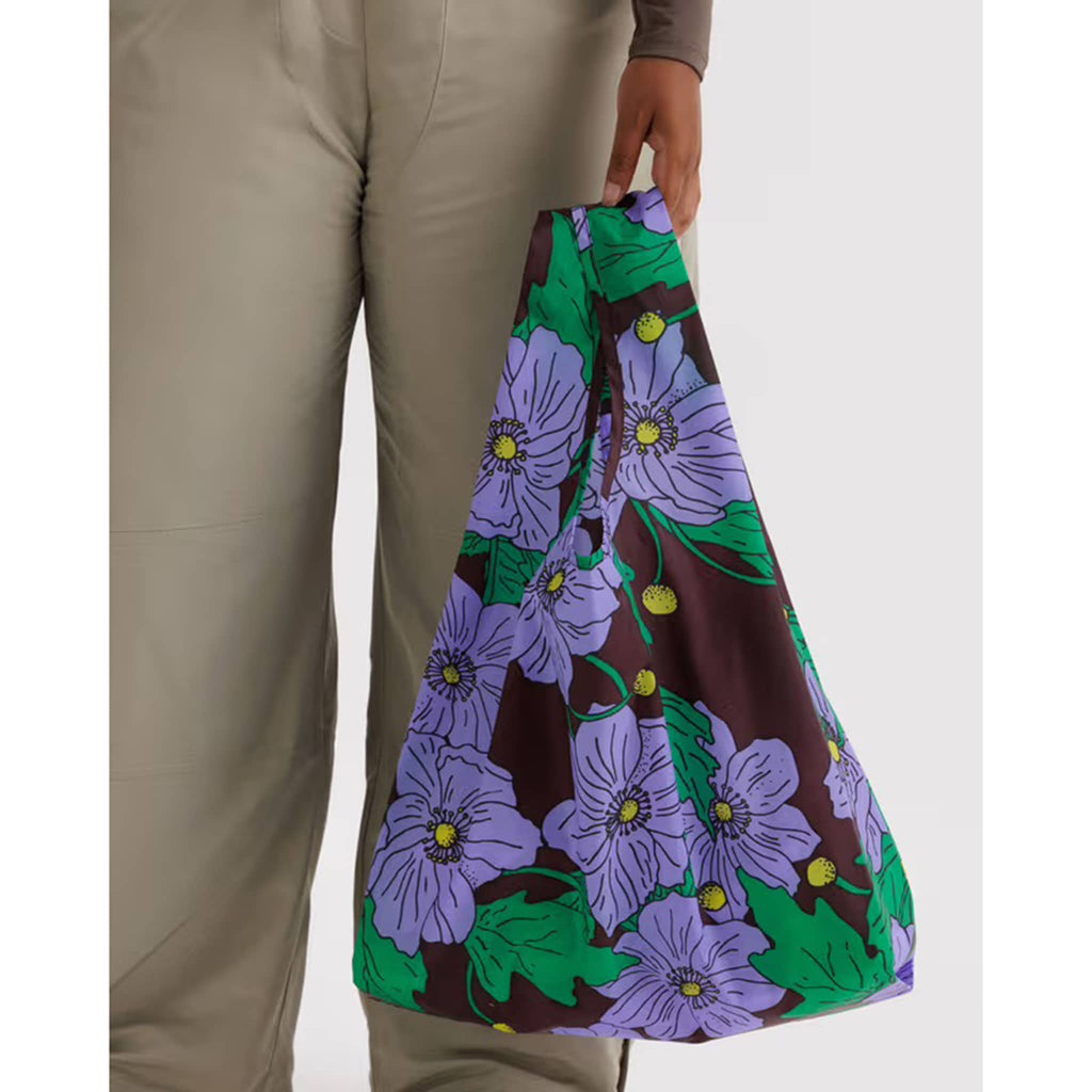 Person holding a colorful floral-patterned bag against a white background.
