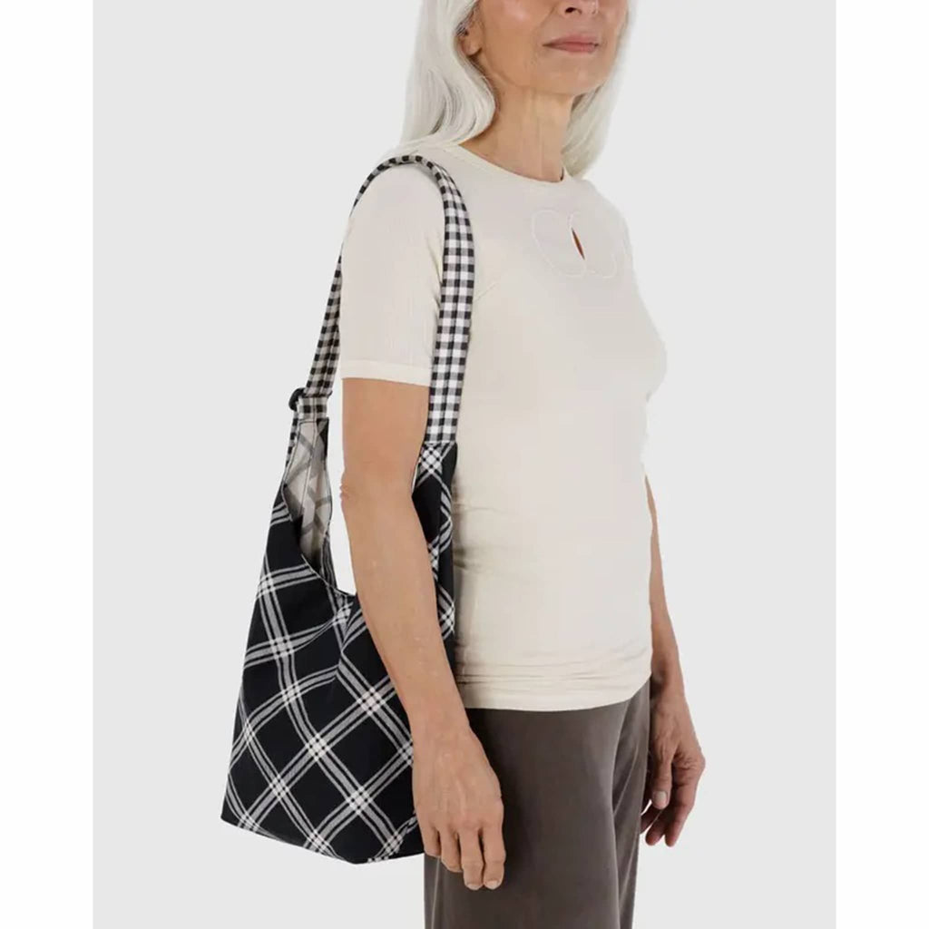 Person holding a black and white plaid bag against a white background.