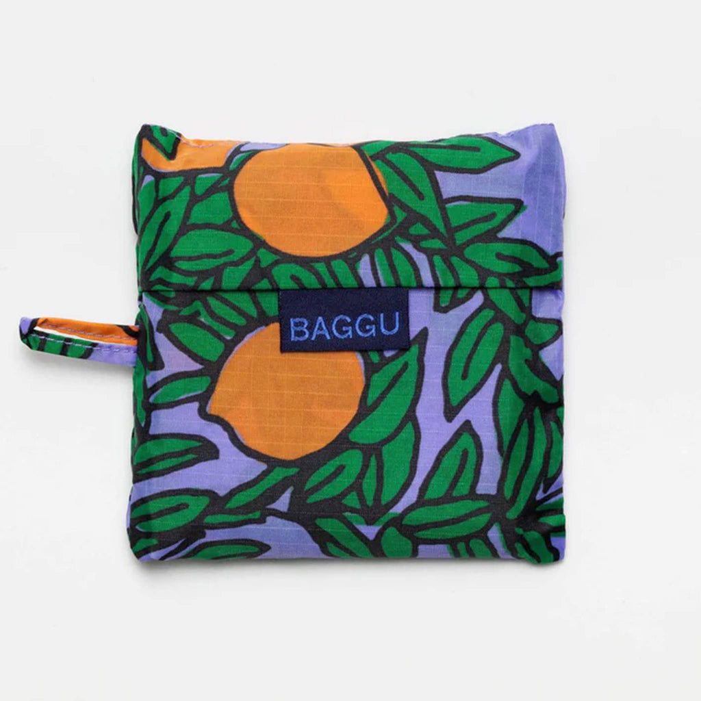 Baggu standard size eco-friendly recycled ripstop nylon reusable tote bag with an orange tree print on a periwinkle backdrop, in matching pouch.