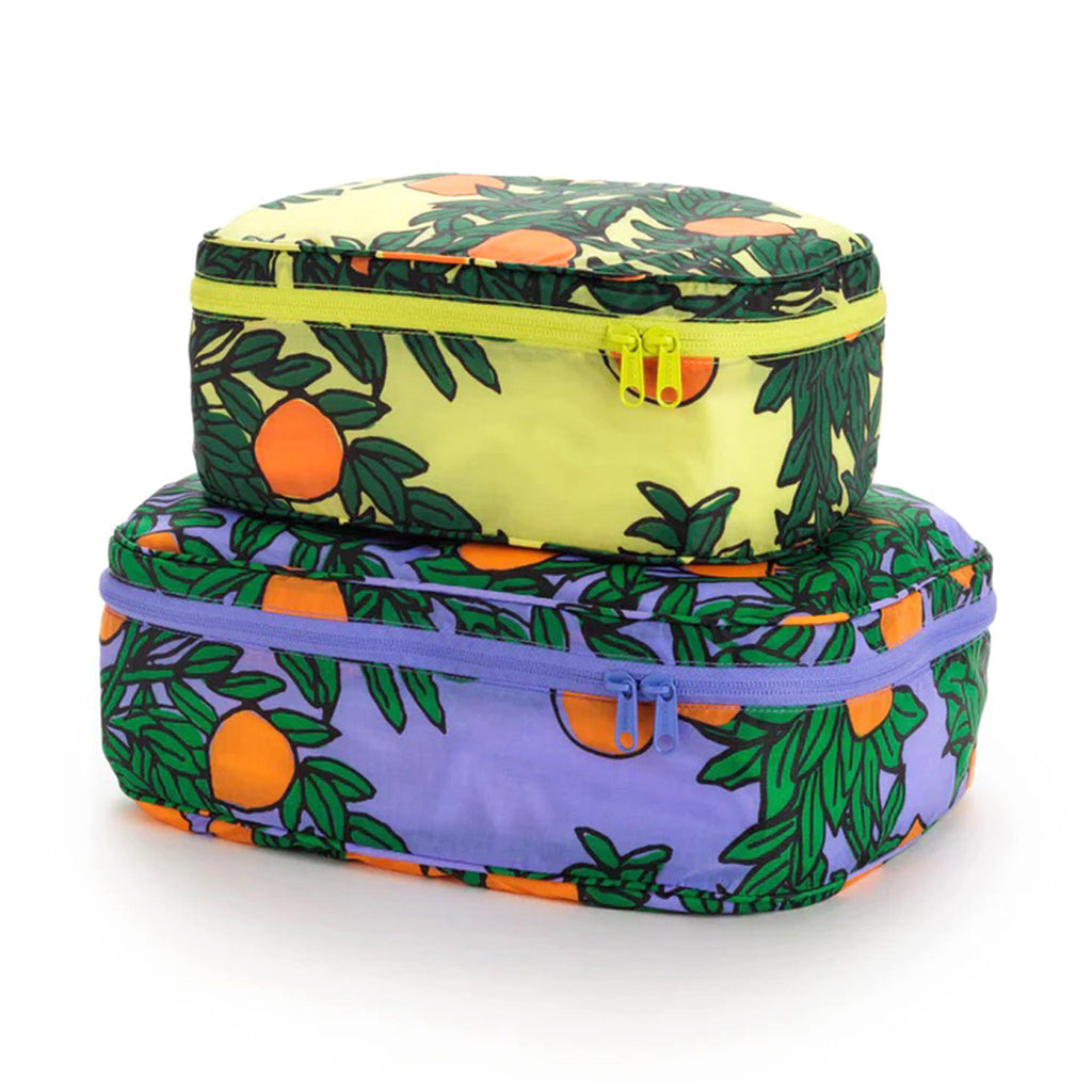 Baggu reusable recycled ripstop nylon packing cube set of 2 with orange trees print, large has a periwinkle backdrop and the small cube has a yellow backdrop, stuffed and stacked.