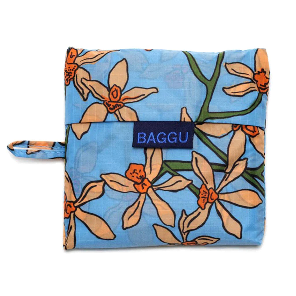 Baggu standard size eco-friendly recycled ripstop nylon reusable tote bag with an orange orchid print on a blue backdrop, in matching pouch.