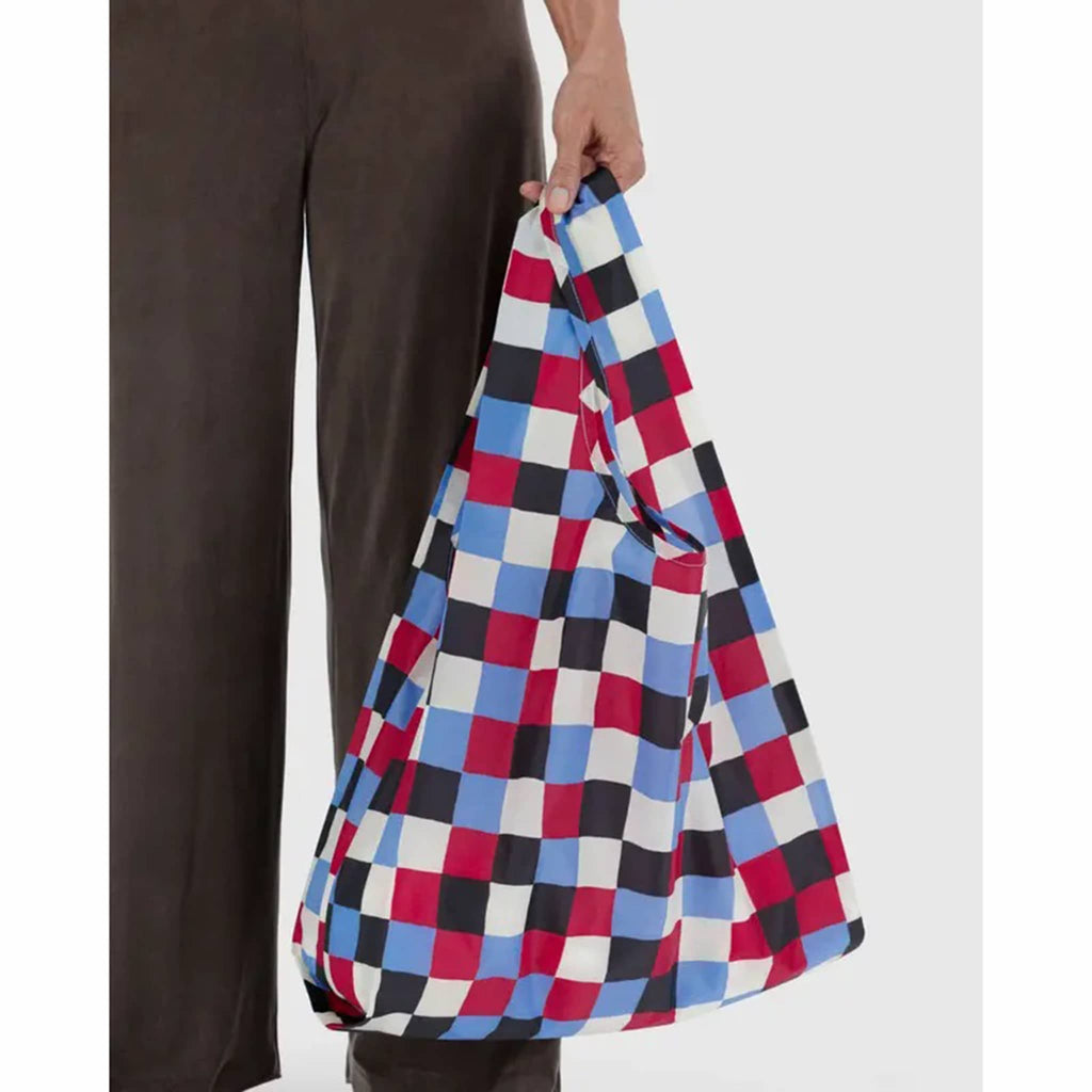 Person holding a multicolored checkered bag against a white background